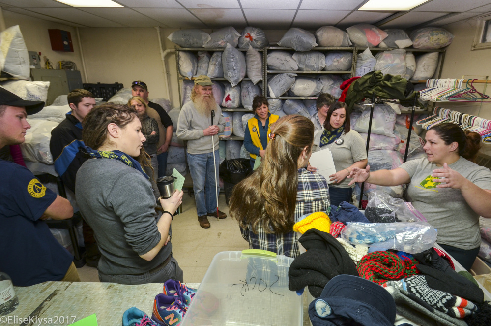 AmeriCorps VISTA volunteers listen Monday to Warming Center Director Deidrah Stanchfield, far right, as she outlines the various tasks to be done during the MLK Day of Service. Volunteers sorted and distributed items from nearly 40 bags of donated items.