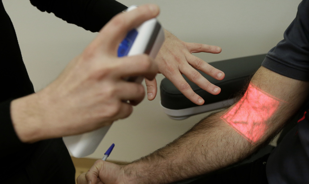 Adrian Aoun demonstrates a vein illumination device that uses infrared light on an Associated Press reporter at a medical office in San Francisco. Aoun says doctors need more up-to-date tools.