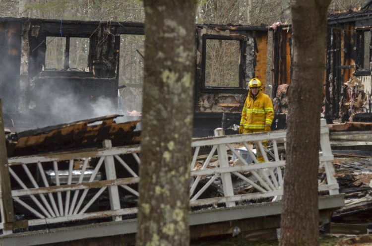 A firefighter walks among the smoldering ashes Monday at the scene of the fatal fire in the Knox County town of Washington.