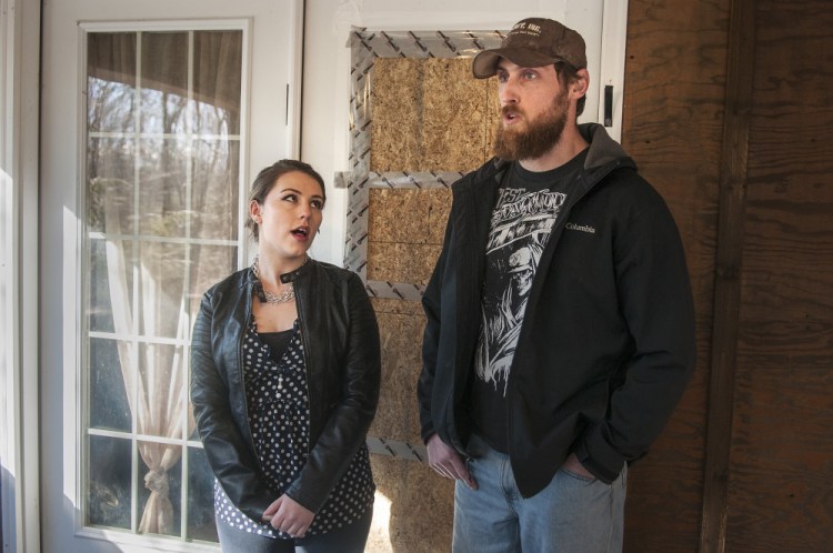 Standing in front of the boarded-over broken window of their front door, Lindsey Levasseur and Trevor Whitney tell the story of an early-morning home invasion on Wednesday at their home in Richmond.