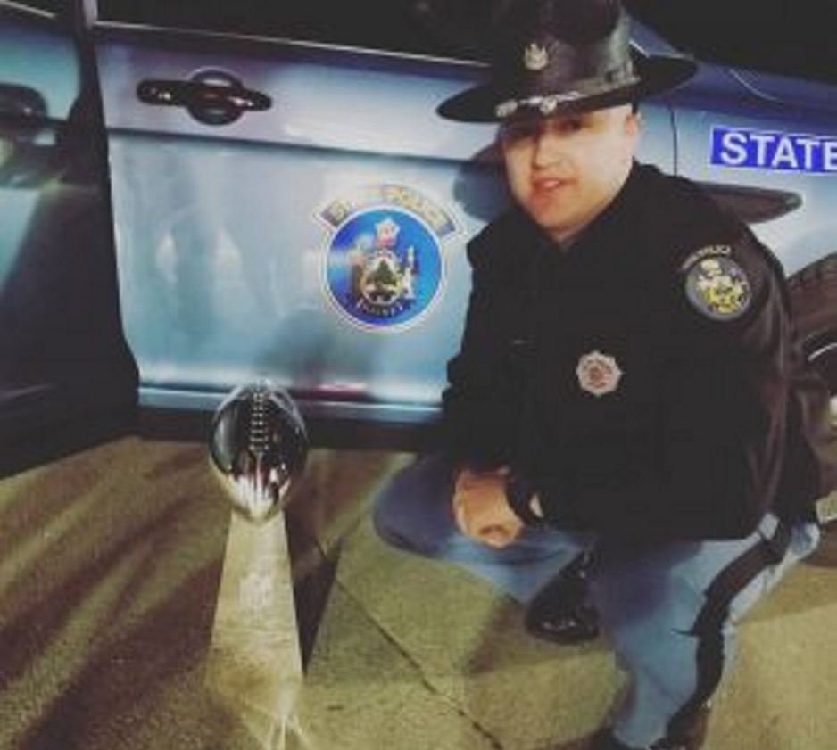 Trooper Tyler Maloon poses next to the Vince Lombardi Trophy after driving its caretakers to Pittsfield after their car struck a deer early Saturday morning on Interstate 95 and became inoperable.