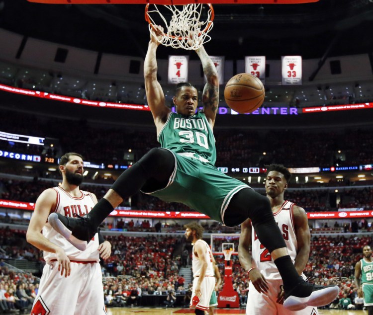 Boston's Gerald Green dunks as Chicago's Nikola Mirotic, left, and Jimmy Butler watch during the first half of Friday night's NBA playoff game at Chicago.