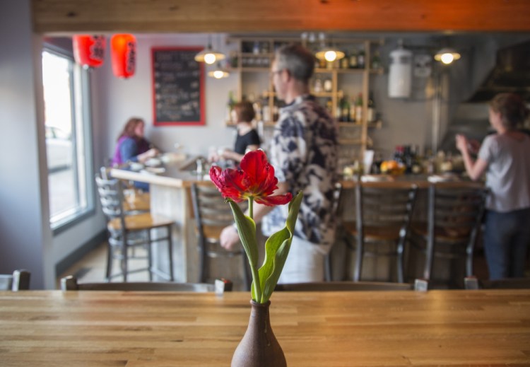 Izakaya Minato seats 37 in two dining rooms, a busy front room anchored by the bar and three-person kitchen, and a quieter back room with small tables and banquette seating.