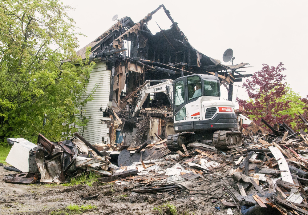 Driving a Bobcat excavator, Bob Anair demolishes 34 Main St. Friday in downtown Richmond. The house, opposite the Old Goat Pub, was damaged by a fire last Christmas.