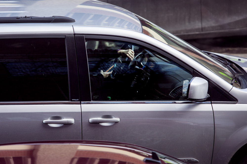 A motorist drives down Temple Street in Portland with one hand on the wheel and one hand on the phone. Researchers have found that hands-free devices are just as great a distraction for drivers as hand-held ones.