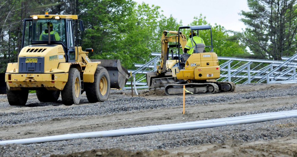 Workers use heavy equipment to bury electrical conduit at the new solar facility under construction near the Waterville campus of Colby College on Monday.