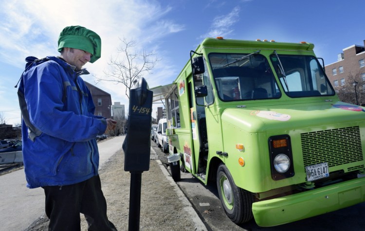 James Dinsmore puts change in a parking meter on Spring Street in Portland in 2014, a year when the city took in about $2.2 million from meters. That amount has been growing each year, with parking meter revenue projected to be $2.7 million this year.