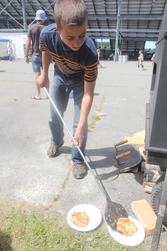 Josiah Lackey, 13, of Parkman slides a couple of wood-fired pizzas onto plates. Fairgoers could also find beer to go with. Photo by Jeff Pouland