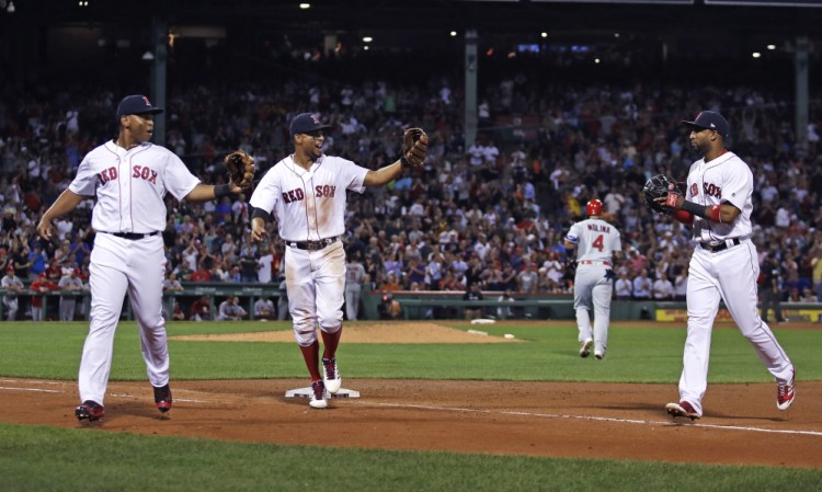 From left, Boston Red Sox third baseman Rafael Devers, shortstop Xander Bogaerts and second baseman Eduardo Nunez, celebrate after turning a triple play on a ground out by St. Louis Cardinals' Yadier Molina during the fourth inning Tuesday in Boston.