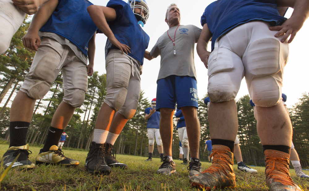 Jim Walsh, head coach for the Sacopee Valley High football team, huddles with players before a drill. Sacopee Valley is returning to varsity status as a member of the new Class E developmental division.