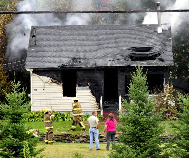 A couple watches as firefighters extinguish a fire that destroyed the home at 230 Lakeview Drive in China on Sept. 18, 2017.