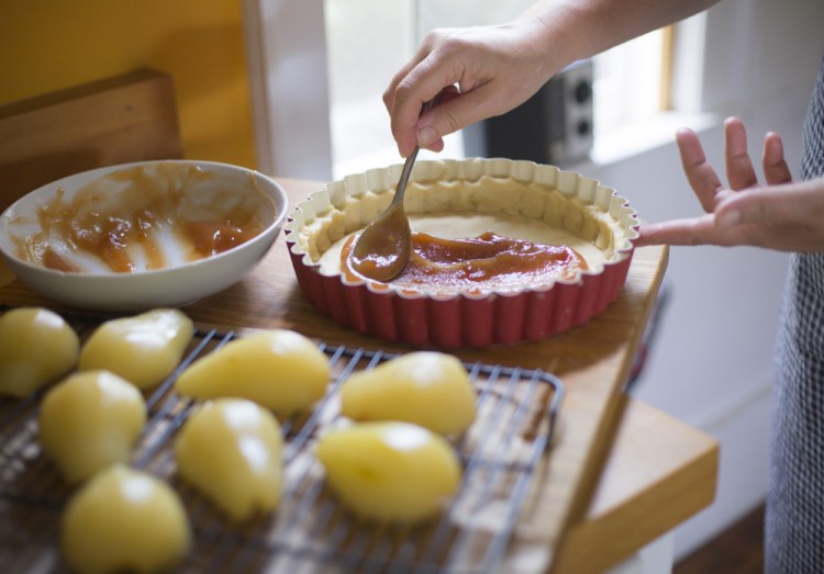 Christine Burns Rudalevige spreads quince jam along the bottom of a chilled crust. Below: The finished tart.