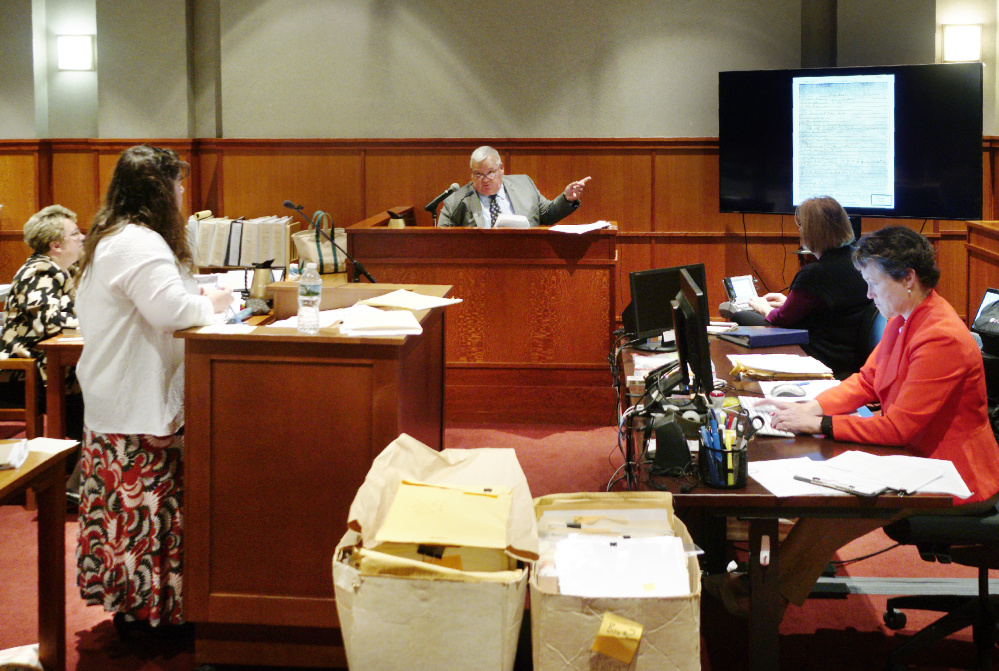 Retired Portland Police Detective Daniel Young answers a question from attorney Amy Fairfield during the fourth day of a post-conviction review for Anthony Sanborn on Friday. Below, Young looks over an investigative report.