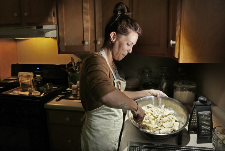 Megan Brown mixes apple slices with flour and spices while making an apple raspberry slab pie at her home in Farmington last week. Brown will be competing in the Maine's Best Baker competition at Ocean Gateway on Saturday.