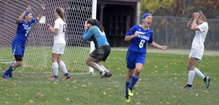 Annie Worthen, 6, and Sydney LeBlanc, left, of Madison start the celebration, and the Monmouth Academy players realize the season is over Wednesday after an overtime goal.