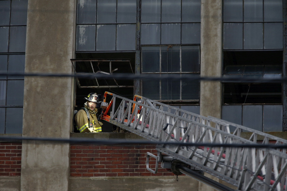 A Sanford firefighter is illuminated by a ladder truck while responding to a fire at the vacant Stenton Trust mill on Thursday. Fires have been a frequent occurrence recently in Sanford.