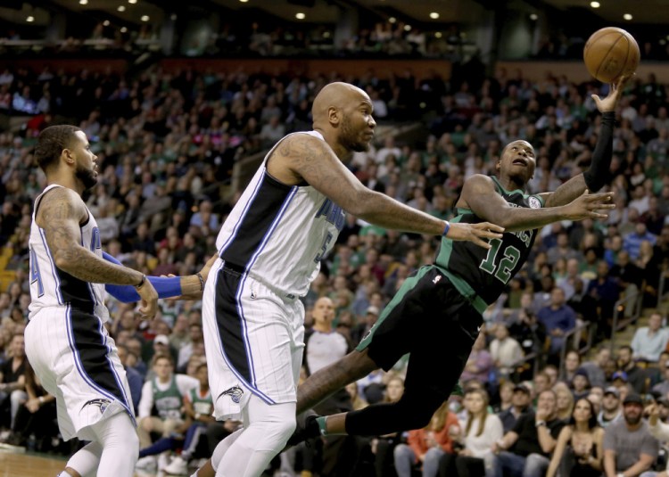 Boston's Terry Rozier drives to the basket ahead of Orlando's Marreese Speights, center, and D.J. Augustin, left, during the first half Friday night in Boston.