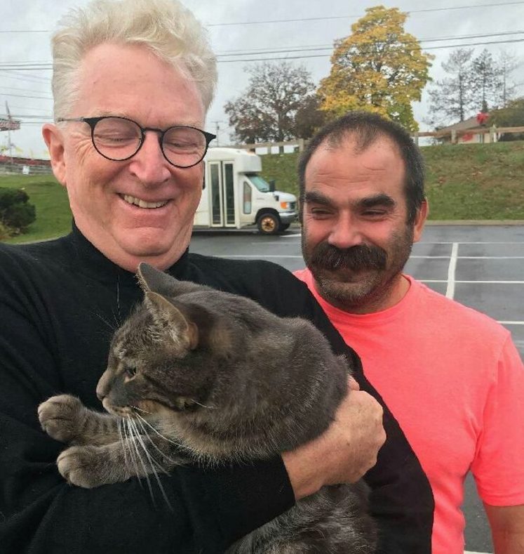 George Lichte of Kennebunkport holds his cat, Romeo, as Kevin Taft of Solon, who found the cat in Unity after it had been missing for a year, watches.