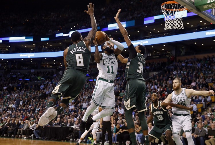 Boston's Kyrie Irving goes to the basket between Milwaukee's Eric Bledsoe (6) and John Henson in the second quarter. Irving led the Celtics with 32 points.