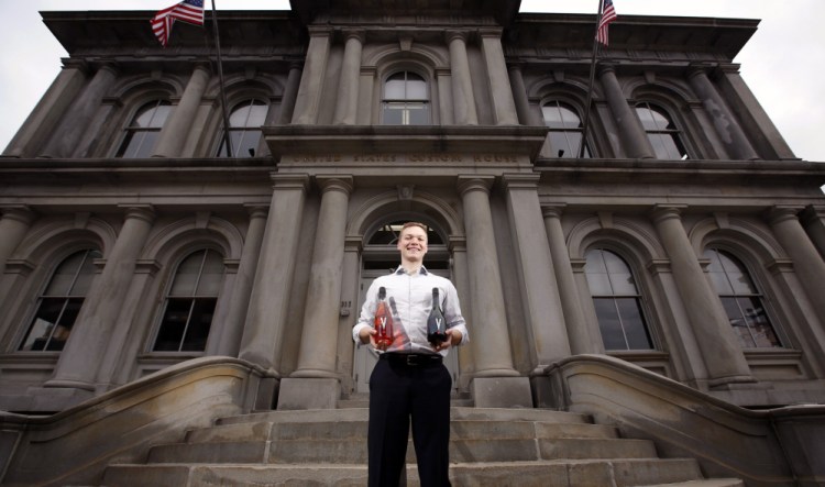 Thomas Brems with two bottles of the Champagne he imports to Maine – a brut rosé, left, and a millésime – in front of the U.S. Custom House in Portland.