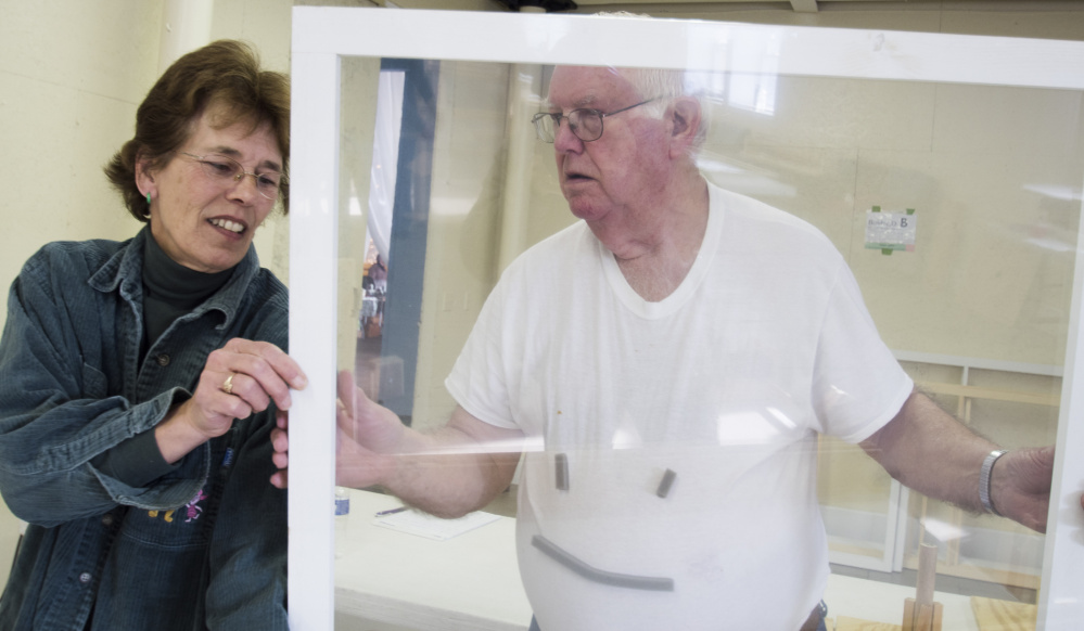 David Bolduc, right, maintenance supervisor of the Vassalboro Historical Society, inspects a wrapped window frame. Volunteers created the plastic window inserts at a community build on Saturday. Bolduc plans on installing the inserts at the historical society's building in East Vassalboro.