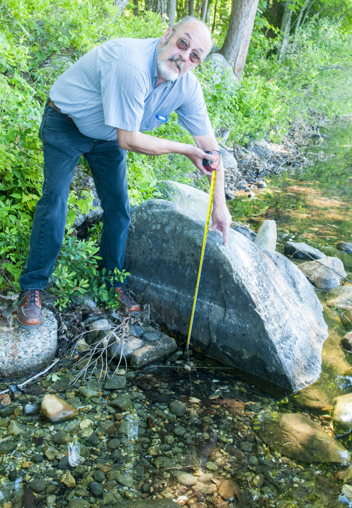 Standing on shore Aug. 2 near his home, John Andrews talks about how low the water was this year on David Pond in Fayette.