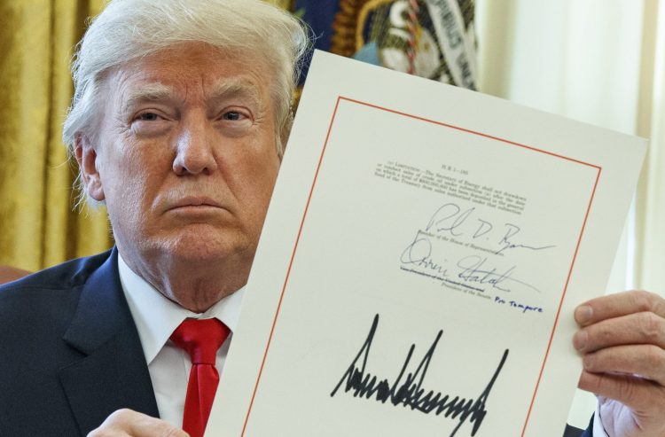 President Trump shows off the tax bill after signing it in the Oval Office on Friday. 