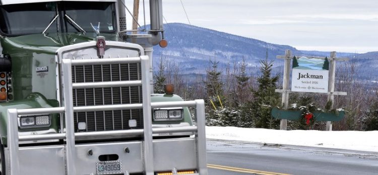 Trucks pass the Jackman town line sign on Route 201. 