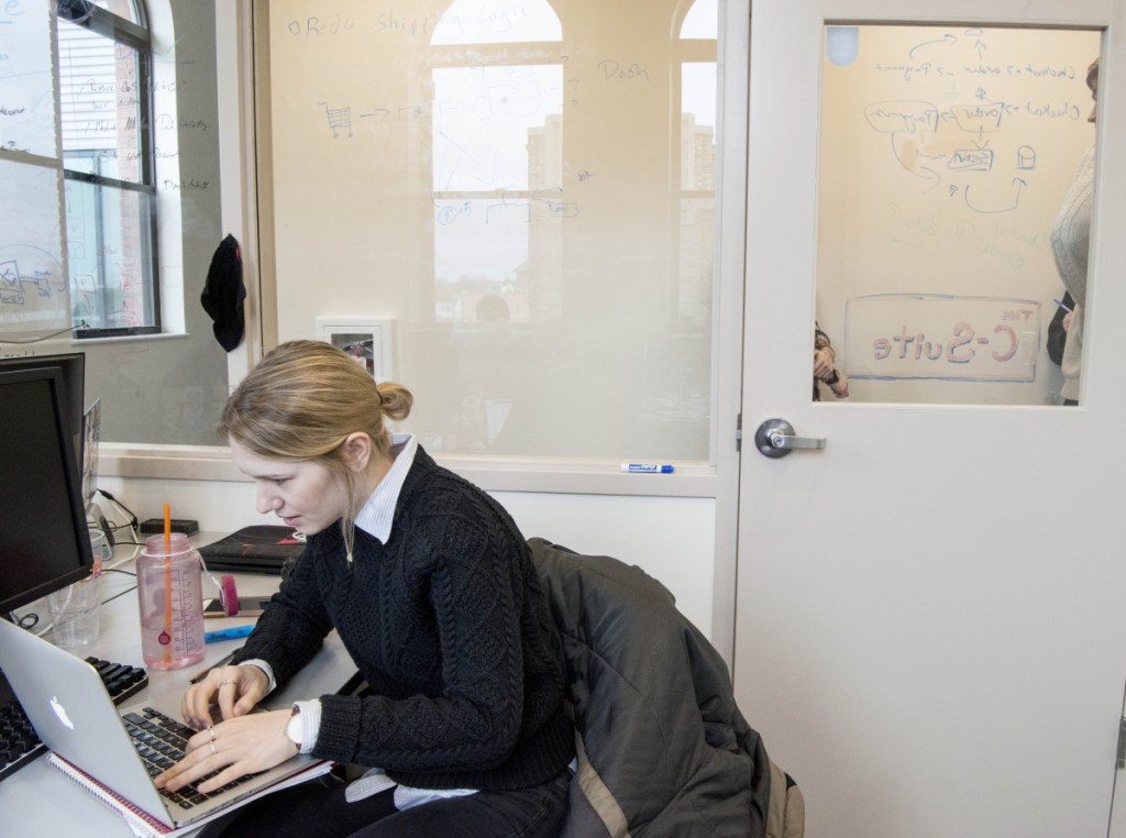 Colby College junior Maddie Taylor, left, works Friday with other classmates at Europiste, an outdoor retail company created by Colby students, as the college continues its commitment to revitalize downtown Waterville with new businesses in the Hains building.