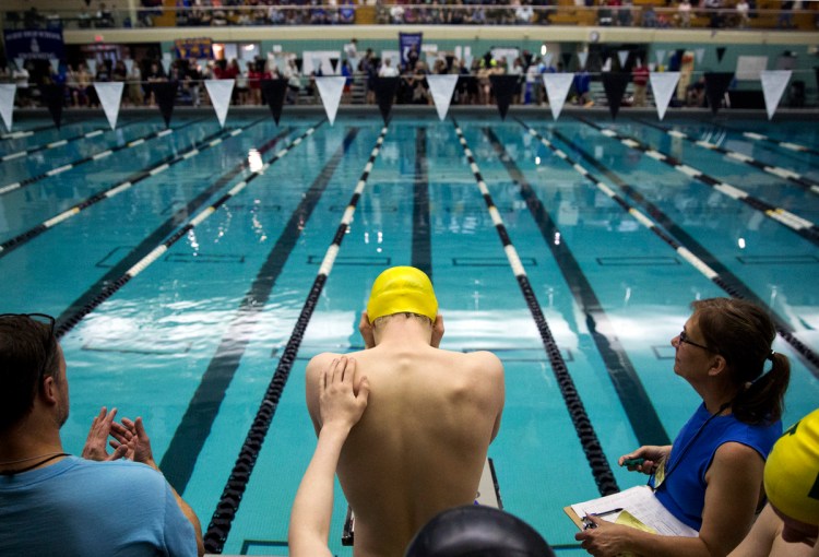 A teammate gives Liam Sullivan, a junior from Mount Desert Island, a reassuring pat on the back before he starts in the 400-year freestyle relay, the last event of the Boys Class B state swimming and diving championship. MDI's second place finish  allowed them to take home the state championship trophy. Sullivan set a meet record in the 200-yard individual medley and another in the 100 backstroke. 