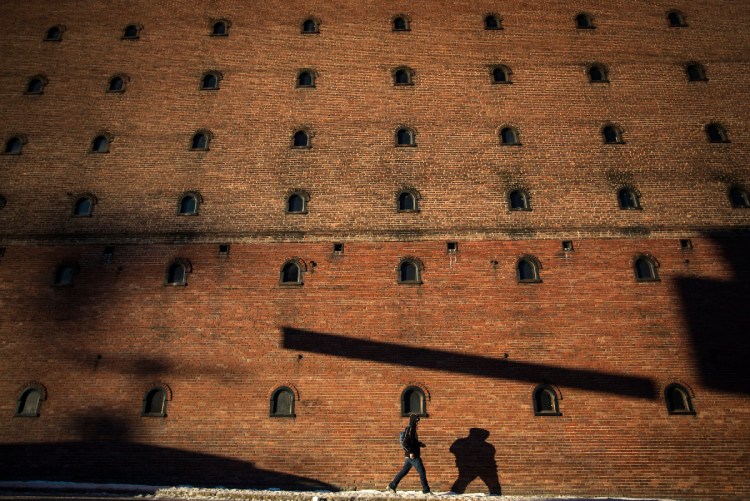 BIDDEFORD, ME - JANUARY 25: A pedestrian casts a shadow on the wall of an old textile mill on Jan. 25, 2018, as he walks along Main Street in Biddeford. Staff photo by Derek Davis