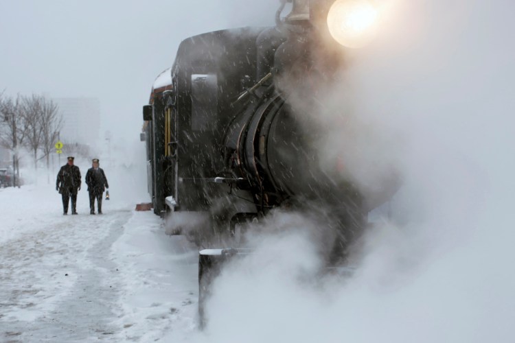 Conductors wait outside the steam-enshrouded "Polar Express" before departing on an afternoon trip along Portland's waterfront. Staff photo by Ben McCanna