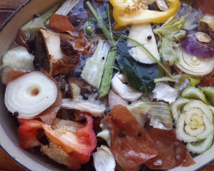 A pot of beef marrow bone stock with lots of vegetable scraps.