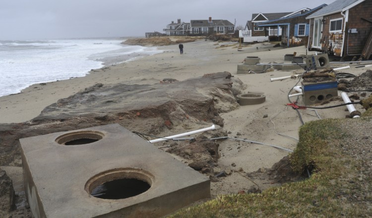 Peter Cook walks the beach to check out the scene at the end of Whitecap Lane in Sandwich, Massachusetts, which was hard hit again by the overnight high tide, on Saturday.