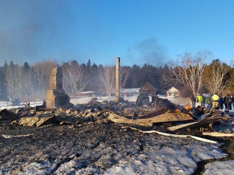 Officials look at the wreckage of the Chesuncook Lake House which started on fire early Saturday morning.