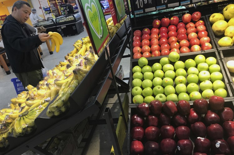 A man chooses bananas near imported apples from the United States at a supermarket in Beijing on Monday.