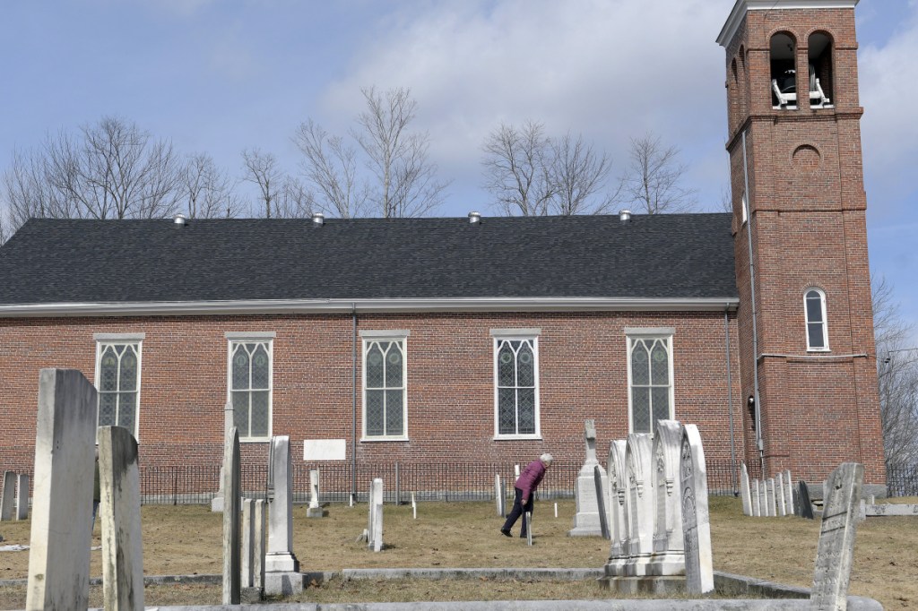 Whitefield archivist Marie Sacks examines a headstone Tuesday at St. Denis Cemetery in Whitefield. Several stones of Irish Catholic immigrants who migrated to the community in the early 19th century were damaged during a recent car crash that remains under investigation.