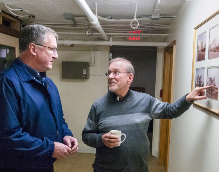 The Rev. John Skehan, left, looks at historical photos with the Rev. Frank Morin during a tour of the St. Michael Pastoral Center on Thursday in Augusta. Skehan will be replacing Morin, who plans to retire July 1. The Pastoral Center is in the former St. Augustine's School building.