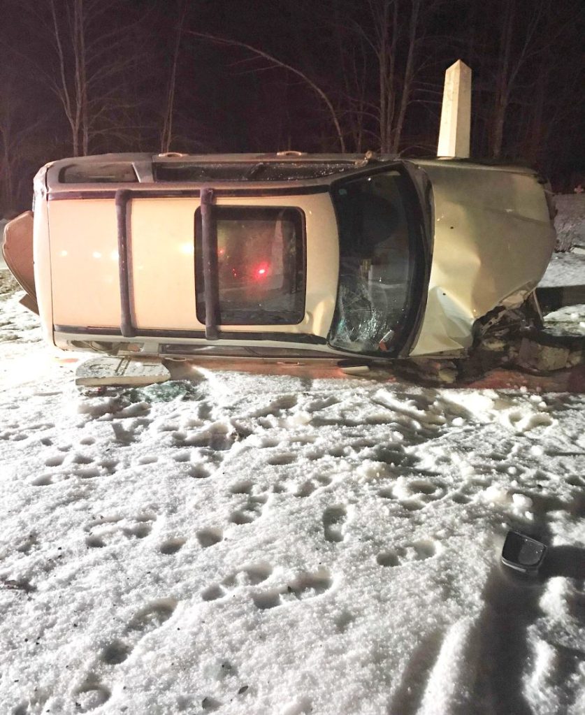 A 2006 Subaru Forester rests on its side March 27, 2018, after a crash that left the driver injured, damaged a fence and toppled gravestones at the cemetery next to St. Denis Church in Whitefield.