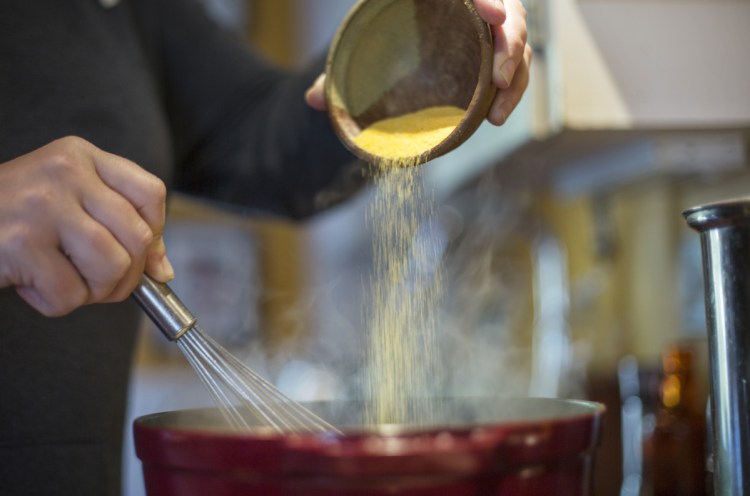 Christine Burns Rudalevige sprinkles polenta into the pot.