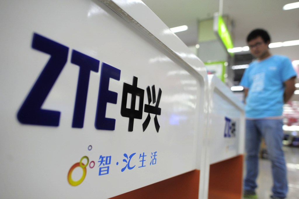 FILE - In this Oct. 8, 2012, file photo, a salesperson stands at counters selling mobile phones produced by ZTE Corp. at an appliance store in Wuhan in central China's Hubei province. The tech company, ZTE, a Chinese tech giant brought to its knees and delayed shipments of imported U.S. cars, apples, lumber and other agricultural products are the early casualties as China and the U.S. exchange salvos in a trade dispute.(Chinatopix Via AP, File)