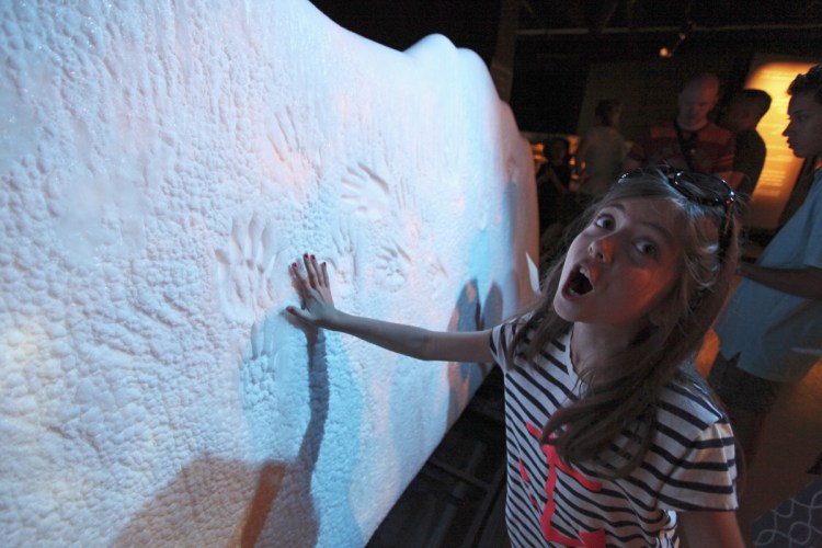 Dinah Routhier, 9, reacts after placing her hand on a sample "glacier" at "Titanic: The Artifact Exhibition" at the Portland Science Center.