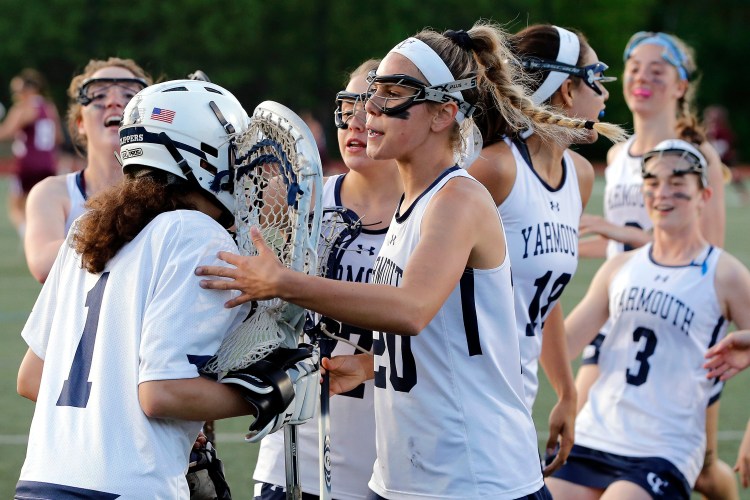 Yarmouth teammates, including captain Greta Elder, center, swarm around goalkeeper Izzy Serrano.