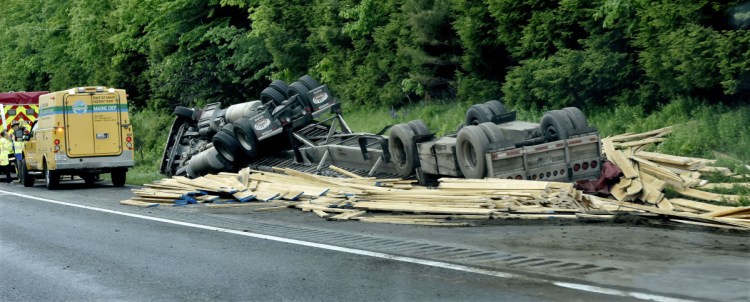 First responders wait for police to reconstruct the tractor-trailer rollover Monday on the southbound side of Interstate 95 in Sidney. The truck was loaded with lumber.