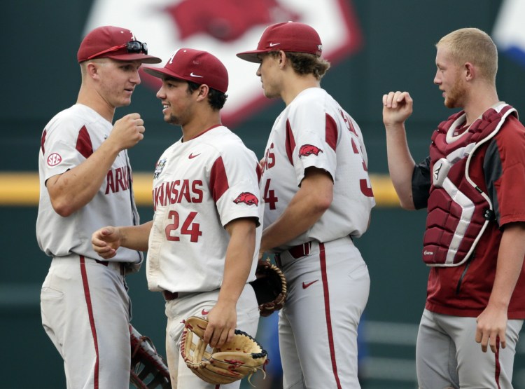 Dominic Fletcher, center, of Arkansas celebrate with teammates after Wednesday's win over TexasTech in Omaha, Neb. Arkansas won 7-4.