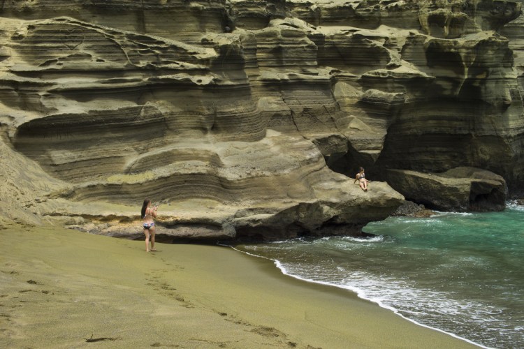 People sunbathe at Papakolea green sand beach near Ocean View, Hawaii, in 2014. The Associated Press has found that stories circulating on the internet that the ongoing eruption of the Kilauea volcano in Hawaii is causing crystals to rain from the sky are untrue.