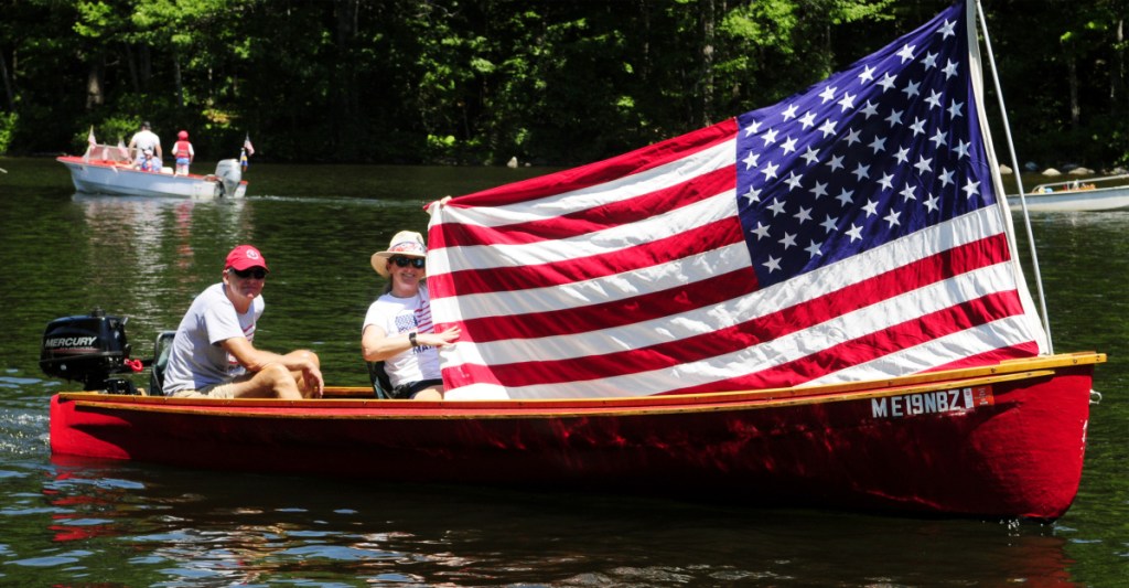 Boaters hold up a large American flag Wednesday during a boat parade on Mill Stream in Belgrade.