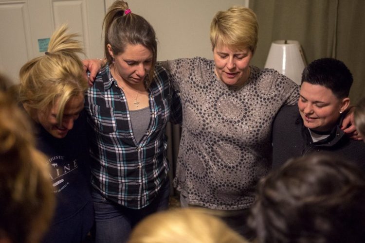 Nichole Curtis, center, who runs a Portland sober house, takes part in the prayer at the end of a 2017 meeting. Maine doesn't regulate sober-living homes or even keep track of where they're located.