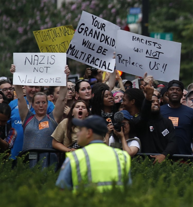 Demonstrators wave signs near the White House to protest a white supremacist rally Sunday in Washington.