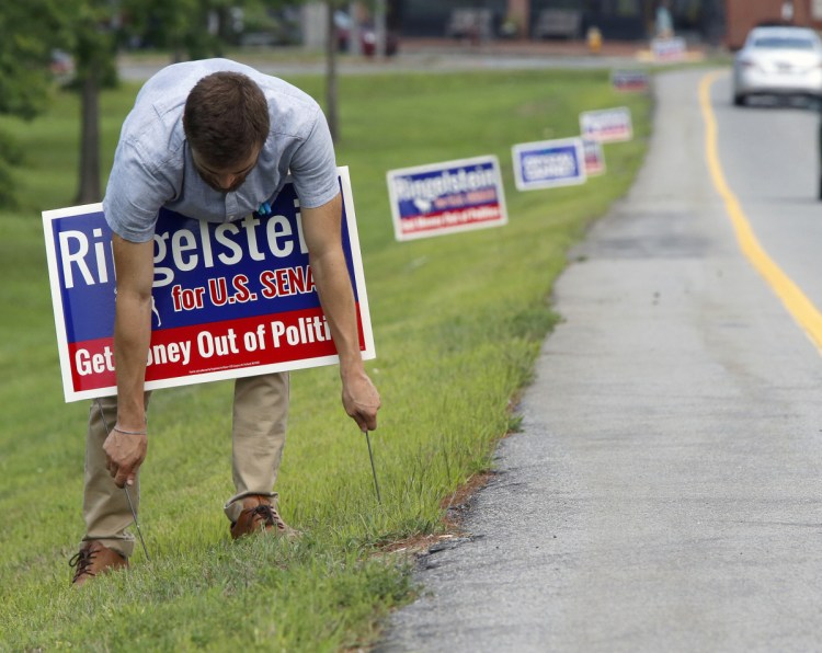 Sammy Potter, assistant to U.S. Senate candidate Zak Ringelstein, erects political signs Thursday along Franklin Street in Portland. Crystal Canney, a candidate for a state Senate seat, had the first signs posted along Franklin Street, prompting some complaints to City Hall.
